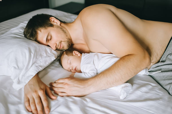 Father and baby sleeping on a bed during daytime
