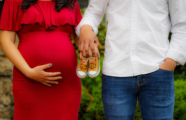 A pregnant woman and her husband holding baby shoes at a baby shower. 