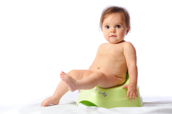 A cute baby sitting on the pot against a white background. Image to demonstrate the issue of baby constipation.