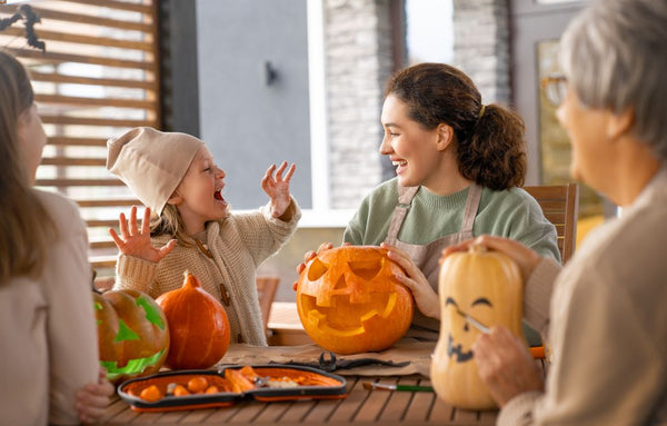 A toddler with family members carving pumpkins and preparing healthy Halloween snacks.